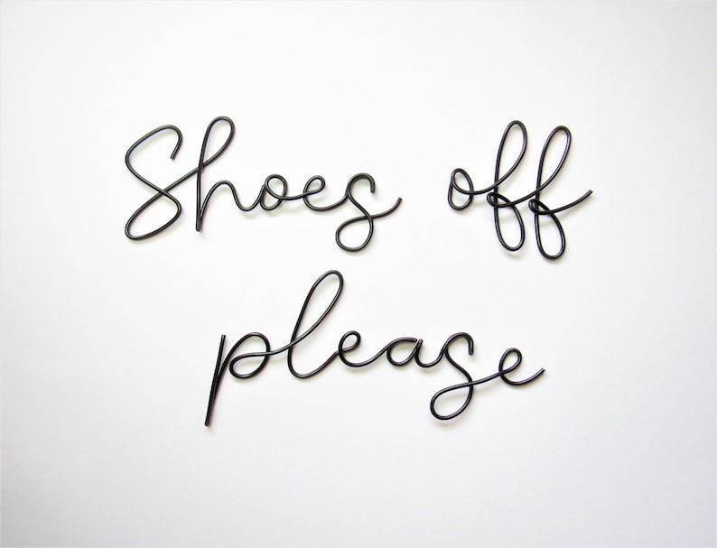 May include: Black wire sculpture sign that reads "Shoes off please".