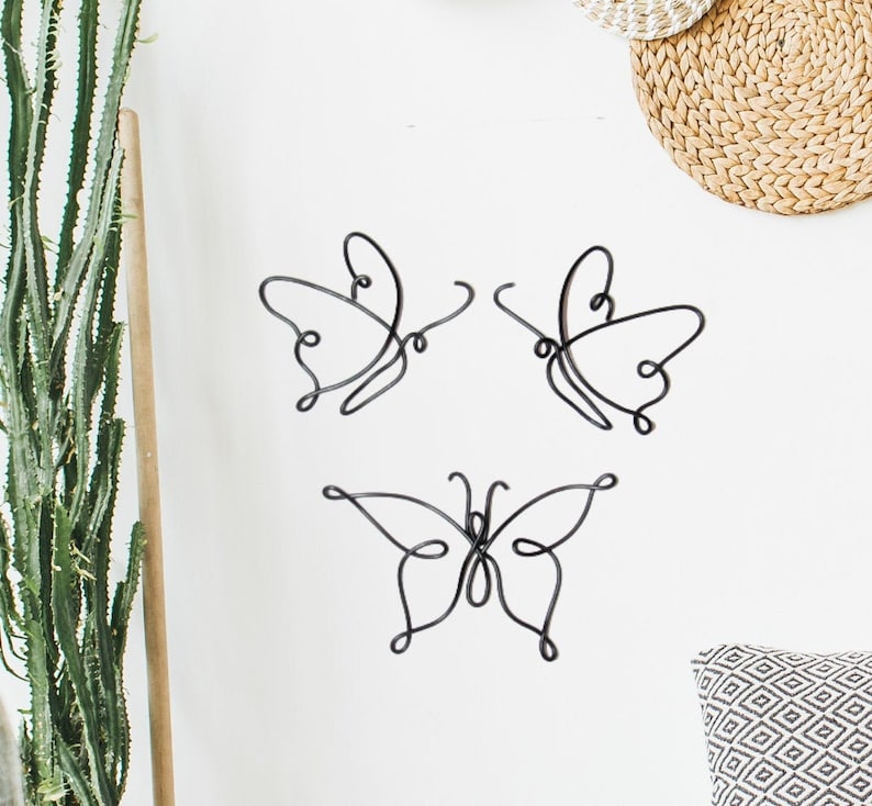 May include: Three black metal butterfly wall sculptures with a simple, minimalist design.