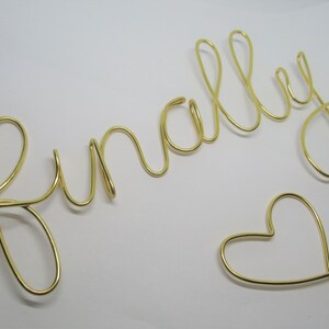May include: Gold wire sculpture of the word "finally" with a heart at the end.