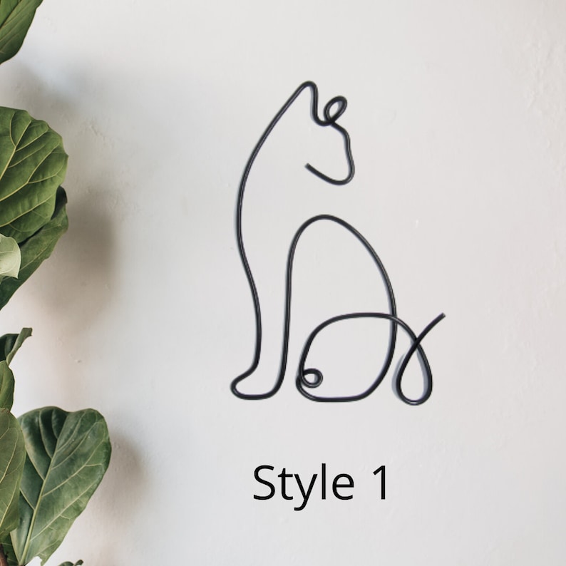 Op de afbeelding: Een zwart draadbeeld van een kat die zit met zijn staart om zijn lichaam gekruld. Het beeld is op een witte muur met de tekst "Style 1" eronder.