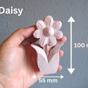 K&ouml;nnte beinhalten: Eine rosa Keramik-G&auml;nsebl&uuml;mchen-Blume mit f&uuml;nf Bl&uuml;tenbl&auml;ttern und einem Mittelkreis. Die Blume ist 10 cm hoch und 5,5 cm breit.