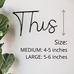 May include: Black metal word art that says "Thus" in a cursive font. The word art is shown with a ruler next to it to show the size options. The size options are: Medium: 4-5 inches and Large: 5-6 inches.
