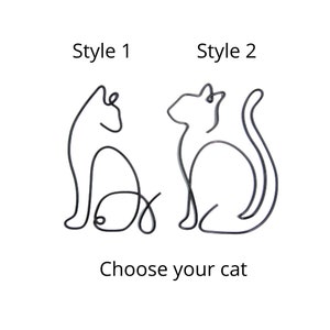 May include: Two wire cat sculptures in different styles. Style 1 is a sitting cat with a curled tail. Style 2 is a cat sitting with its tail curled around its body. The text "Choose your cat" is below the images.