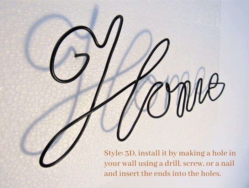 May include: Black metal wire sculpture of the word "Home" with a shadow cast on a white background. The sculpture is 3D and can be installed by making a hole in the wall and inserting the ends into the holes.