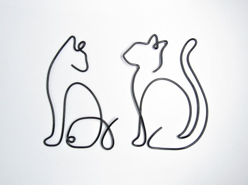 May include: Two black wire sculptures of cats, one sitting and one standing, on a white background.