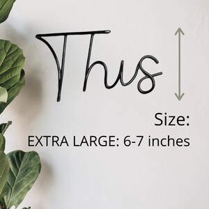 May include: Black metal word art that says "Thus" in a cursive font. The word art is 6-7 inches tall.