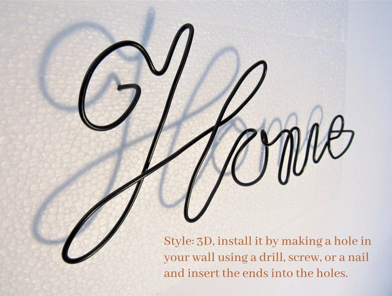 May include: Black metal wire sculpture of the word "Home" with a shadow cast on a white background. The sculpture is 3D and can be installed by making a hole in the wall and inserting the ends into the holes.