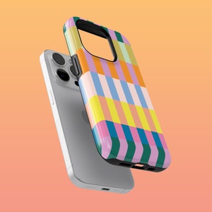 May include: A vibrant phone case featuring a geometric design of vertical stripes in shades of pink, orange, yellow, blue, and green. The case is displayed beside a silver smartphone, set against a soft orange backdrop.