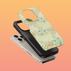 May include: A white iPhone case with a floral pattern featuring green leaves, pink flowers, and blue birds. The case is shown on top of a white iPhone.