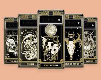 Può includere: Cinque custodie per telefono nere con bordi dorati e diversi design di carte dei tarocchi. I design includono Gli Amanti, la Morte, il Mondo, la Regina degli Anelli e 8 di Bacchette.
