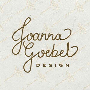 May include: A logo design featuring the name "Joanna Goebel" in elegant, flowing script, with "DESIGN" below in a simple sans-serif font. The text is a warm brown color against a textured, off-white background.