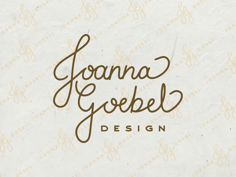 May include: A logo design featuring the name "Joanna Goebel" in elegant, flowing script, with "DESIGN" below in a simple sans-serif font. The text is a warm brown color against a textured, off-white background.