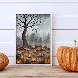 Puede incluir: Una pintura de acuarela enmarcada representa una escena de Halloween. Un árbol nudoso con cuervos se encuentra en un campo de calabazas. Dos calabazas naranjas están sobre la superficie de madera frente a la pintura.
