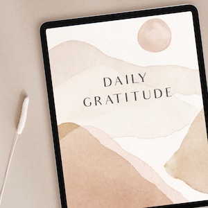 May include: A digital tablet displaying a daily gratitude journal with a watercolor background of abstract shapes in shades of brown and beige. The text "DAILY GRATITUDE" is centered on the screen.