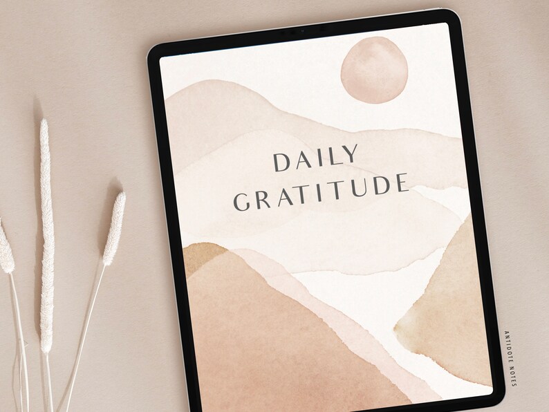 May include: A digital tablet displaying a daily gratitude journal with a watercolor background of abstract shapes in shades of brown and beige. The text "DAILY GRATITUDE" is centered on the screen.
