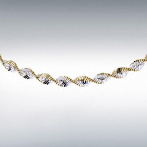 May include: A gold and silver-toned necklace with a twisted rope design. The necklace is made of alternating sections of gold and silver metal, creating a textured and eye-catching pattern. The jewelry is displayed against a white background.