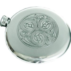 May include: A silver pewter hip flask with a circular design featuring three interlocked spirals and star-shaped accents.