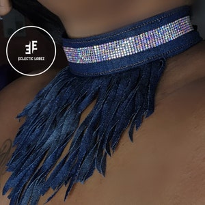 May include: A dark blue denim choker necklace with a fringe trim and a row of iridescent rhinestones.