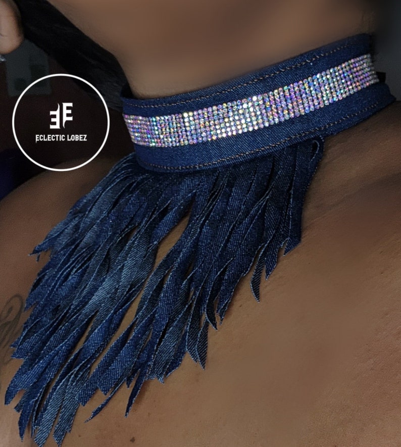 May include: A dark blue denim choker necklace with a fringe trim and a row of iridescent rhinestones.
