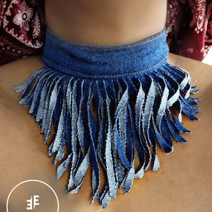 May include: A denim choker necklace with a fringe trim. The fringe is made of denim strips and is about 6 inches long. The choker is about 1 inch wide. The choker is blue and the fringe is blue and white.