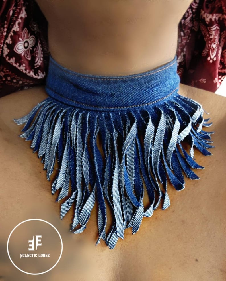 May include: A denim choker necklace with a fringe trim. The fringe is made of denim strips and is about 6 inches long. The choker is about 1 inch wide. The choker is blue and the fringe is blue and white.