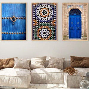 Op de afbeelding: Drie ingelijste prints van blauwe deuren met ingewikkelde details. De meest linkse print toont een verweerde blauwe deur met een metalen ringgreep. De middelste print toont een geometrisch patroon van blauwe, groene, oranje en witte tegels. De meest rechtse print toont een dubbele blauwe deur met een decoratieve boog.