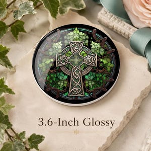 May include: A 9.14 cm glossy circular coaster featuring a central silver Celtic cross with intricate knotwork patterns, surrounded by a vibrant green stained glass design of ivy leaves and vines set against a dark circular border.