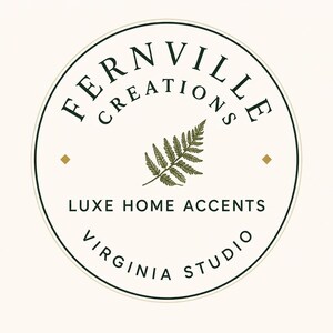 Circular brand logo for Fernville Creations featuring a central green fern frond illustration and black text inside a double border.