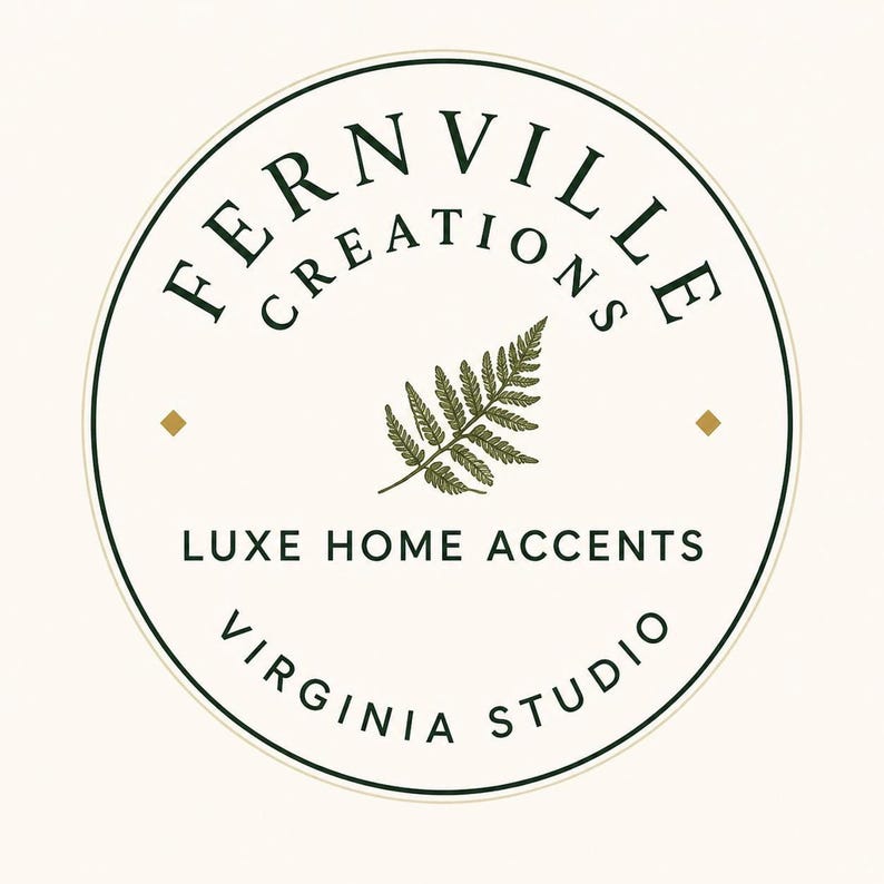 Circular brand logo for Fernville Creations featuring a central green fern frond illustration and black text inside a double border.