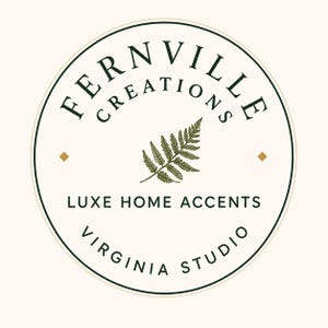 May include: A circular logo on a cream background featuring the dark green text FERNVILLE CREATIONS arched at the top. A central dark green fern leaf graphic is flanked by two small gold diamonds. Below, the text reads LUXE HOME ACCENTS and VIRGINIA STUDIO.