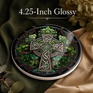 May include: A 10.8 cm glossy round coaster featuring a Celtic cross design with intricate knotwork patterns. The cross is surrounded by vibrant green ivy leaves and dark brown vine accents, all set against a dark, circular background.