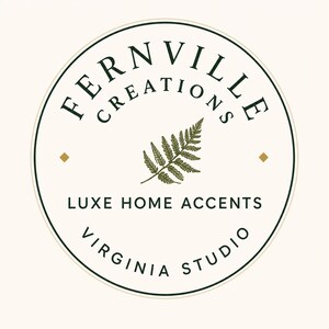 May include: Circular logo with the text "FERNVILLE CREATIONS" in a dark green font, with "LUXE HOME ACCENTS" and "VIRGINIA STUDIO" below. A green fern leaf is in the center. The background is off-white with two small gold squares.