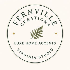 A cream-colored square with a circular logo in the center, featuring the words "FERNVILLE CREATIONS" and "LUXE HOME ACCENTS VIRGINIA STUDIO" in black text, with a green fern illustration.