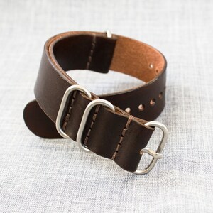 Puede incluir: Una correa de reloj de cuero marr&oacute;n con herrajes plateados. La correa tiene un borde cosido y est&aacute; dise&ntilde;ada para un reloj con una anchura de leng&uuml;eta de 20 mm.