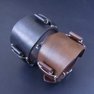 Puede incluir: Dos correas de reloj de cuero, una negra y otra marr&oacute;n, con costuras blancas y hebillas met&aacute;licas.