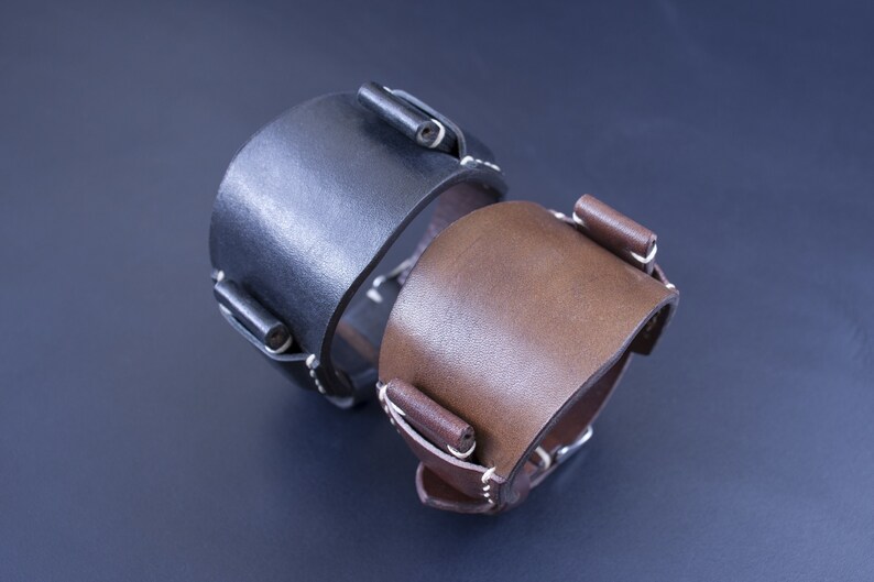 Puede incluir: Dos correas de reloj de cuero, una negra y otra marr&oacute;n, con costuras blancas y hebillas met&aacute;licas.
