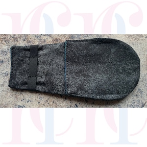 May include: A black fabric pouch with a black elastic strap. The pouch has a blue seam on the side.