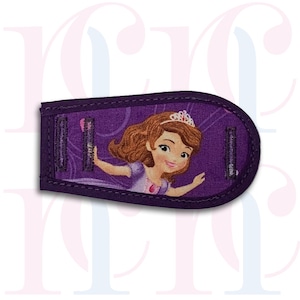 May include: Purple fabric eye patch featuring a princess character from the animated series Sofia the First. The princess is wearing a purple dress and a crown. The eye patch has a velcro fastening.