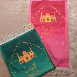 May include: Two personalized prayer rugs with gold mosque designs and Arabic text. The green rug says "Kayden" and the pink rug says "Siyiana".