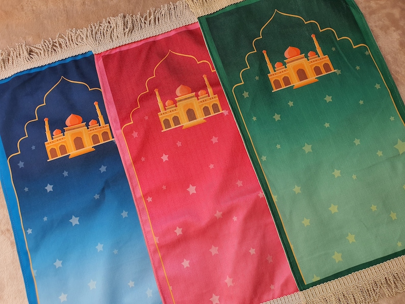 May include: Three prayer rugs with fringe edges. The rugs are blue, pink, and green with a gold mosque design and white stars.