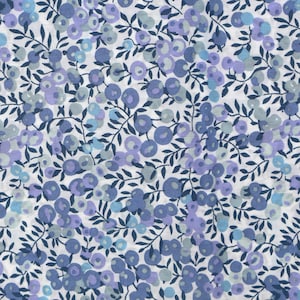Peut inclure: Un tissu blanc avec un motif répétitif de brindilles florales bleues et violettes. Le motif présente de petites formes rondes ressemblant à des baies ou des fleurs.