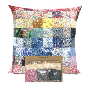 May include: Square patchwork pillow with a variety of floral fabric squares in shades of red, pink, yellow, green, and blue. A small kit with fabric samples and a zipper is in front of the pillow. The pillow is handmade.
