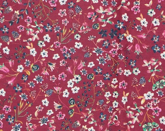 Pode incluir: Um tecido vermelho com um padrão floral branco e rosa. O tecido está coberto de pequenas flores e folhas.