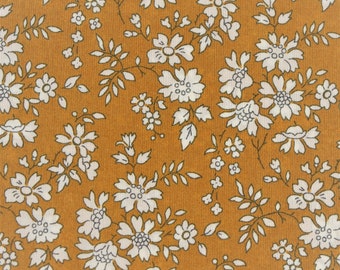 Puede incluir: Una tela marrón con un patrón floral blanco. Las flores son pequeñas y delicadas, y la tela tiene una textura sutil.