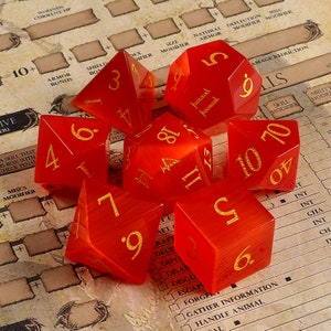 May include: Set of six red, translucent dice with gold numbers. The dice are in various positions on a brown surface with a game board.