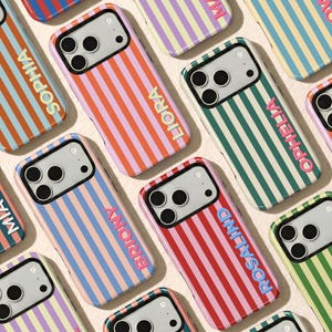 May include: A collection of smartphone cases featuring vertical stripes in various colour combinations. Each case displays a personalised name in raised, contrasting letters. The cases have a cutout for a triple-lens camera system.