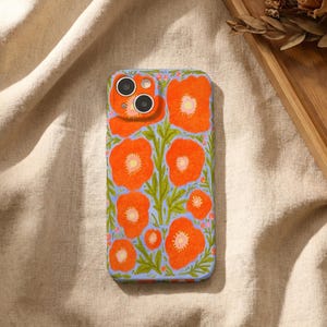 Puede incluir: Una funda rectangular para smartphone con una ilustraci&oacute;n vibrante de amapolas de color naranja brillante con centros amarillos y tallos verdes sobre un fondo azul b&iacute;garo claro. La funda tiene un recorte para un sistema de c&aacute;mara dual.