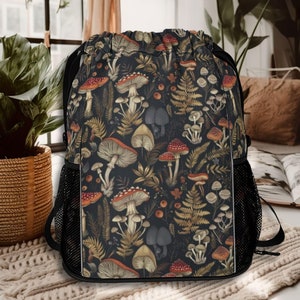 May include: A black drawstring backpack with a mushroom and fern pattern. The pattern features red, brown, and white mushrooms, green ferns, and gold accents on a dark background.