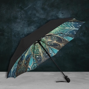 Puede incluir: Un paraguas negro y azul con un diseño de árbol dorado y verde. El paraguas está abierto y el mango es visible.