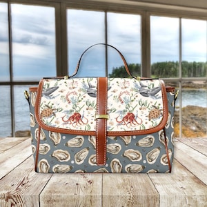 May include: A brown leather handbag with a blue and white fabric pattern featuring sea life, including whales, octopuses, and oysters. The bag has a top handle and a shoulder strap.